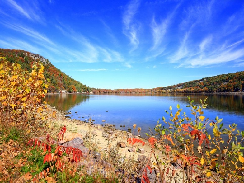 Autumn foliage along calm lake shoreline, hiking trails at Devil's Lake State Park, Wisconsin