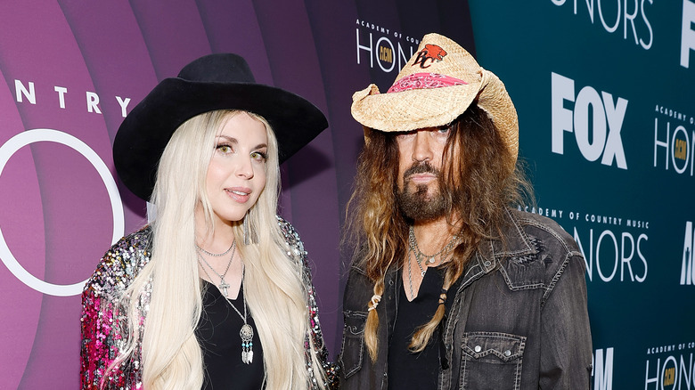 Billy Ray Cyrus poses with Firerose on red carpet