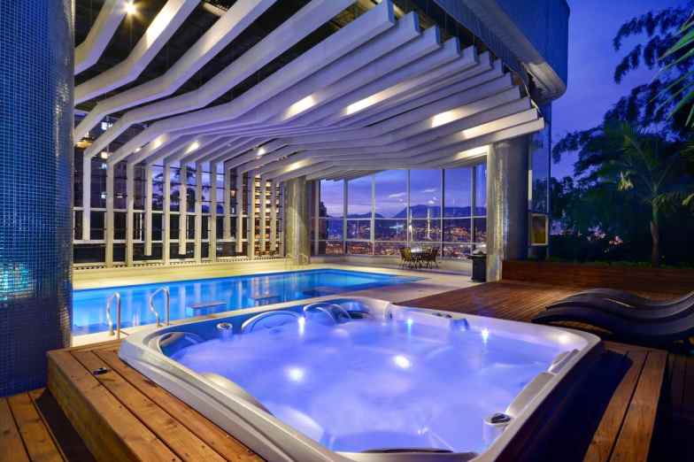Indoor outdoor pool with hot tub at nighttime