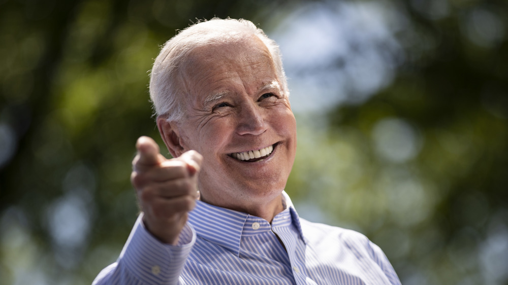 Joe Biden smiling while looking up and pointing a finger out