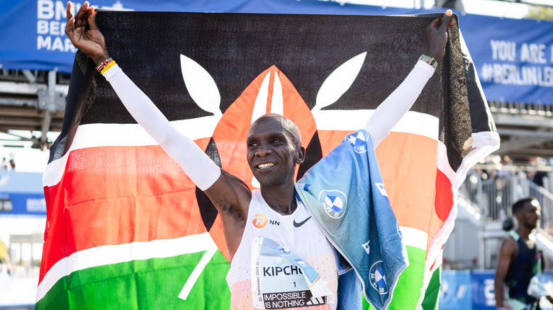 Eliud Kipchoge celebrates victory with flag behind him