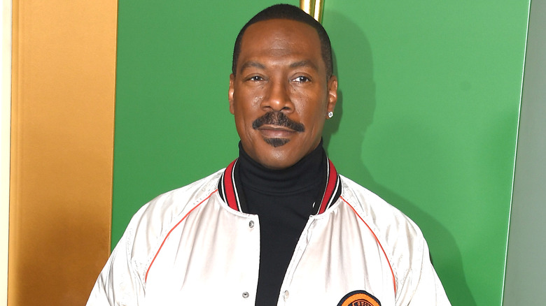 Eddie Murphy wearing a black turtleneck and white jacket