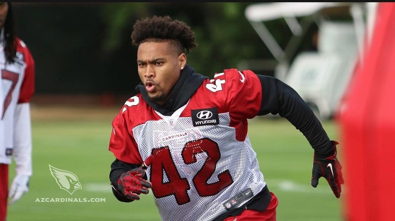 Jonathan Owens wearing a black long-sleeved hoodie underneath a red and white football jersey