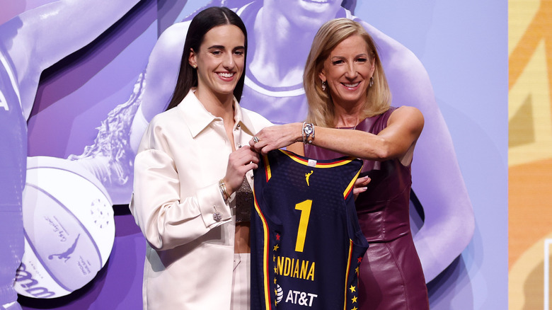 Caitlin Clark posing with Indiana jersey at WNBA draft