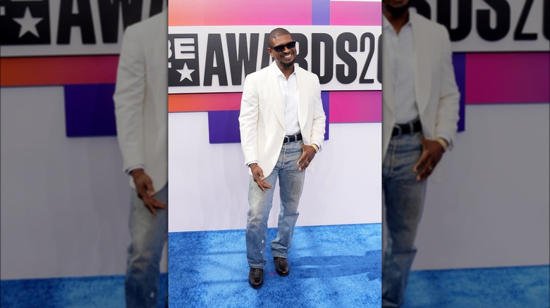 Usher posing in white shirt and jeans