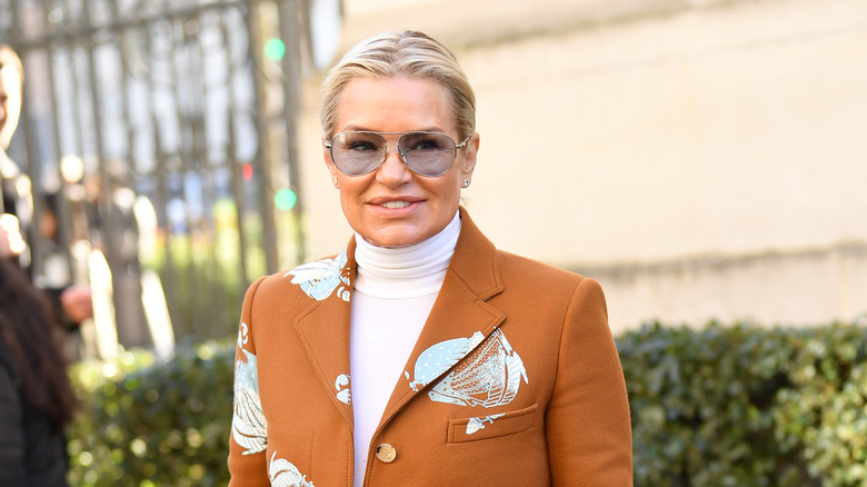 Yolanda Hadid smiling in front of a bush